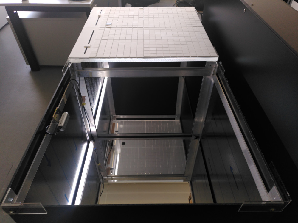 image of table with acrylic glass grid and sliders on top and mirrors and LED light below